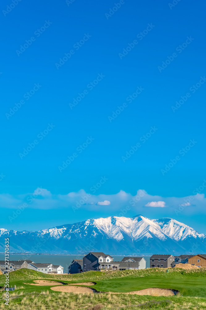 Vivid blue sky with clouds over a lake and snow capped mountain on a sunny day