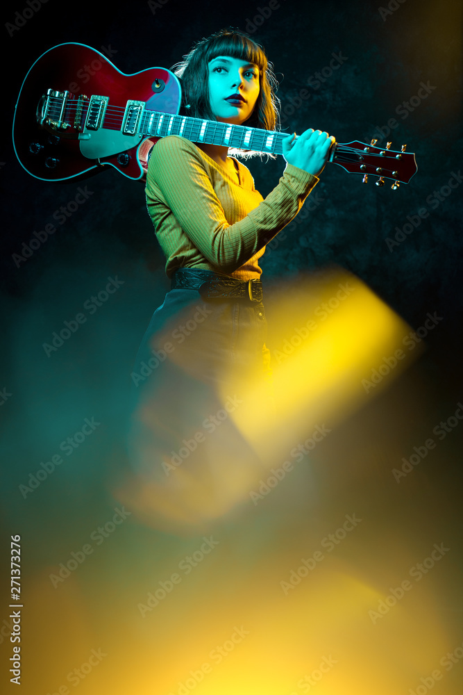 Beautiful young hipster woman with curly hair with red guitar in neon  lights. Rock musician is playing electrical guitar. 90s style concept.  Stock Photo | Adobe Stock