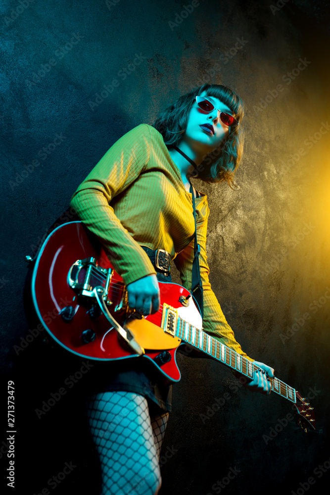 Beautiful young hipster woman with curly hair with red guitar in neon  lights. Rock musician is playing electrical guitar. 90s style concept.  Stock Photo | Adobe Stock
