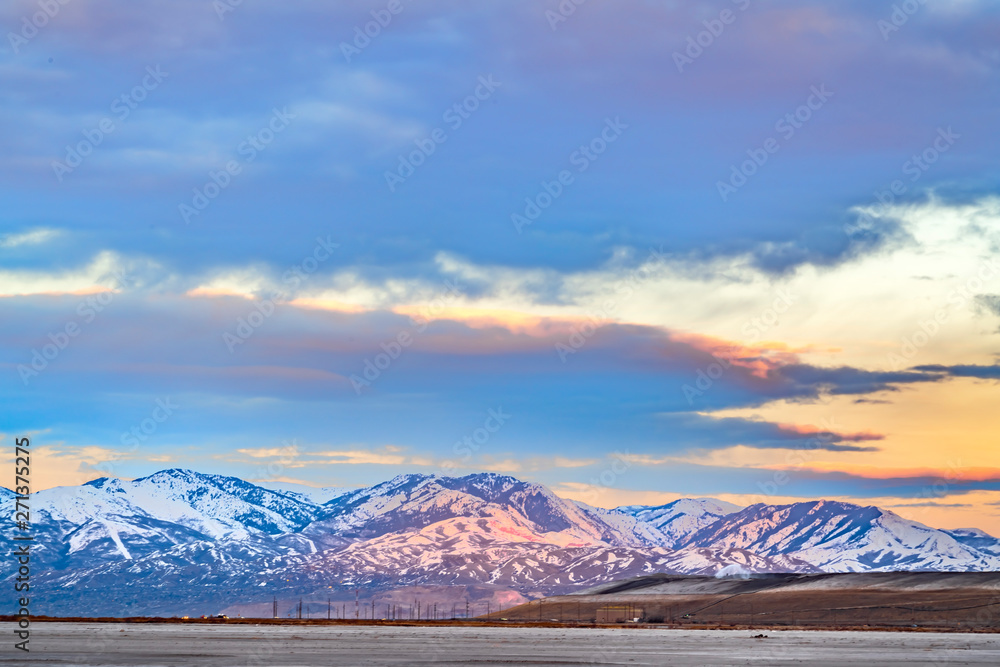 Panorama of a magnificent snow covered mountain beyond a lake at sunset
