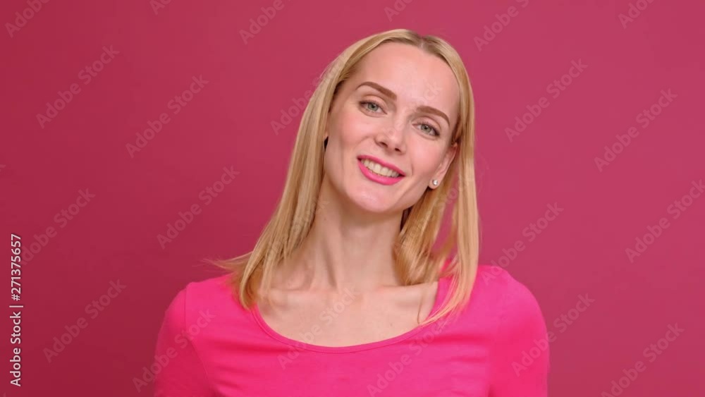 Attractive young woman blonde in a red T-shirt and jeans posing on a pink background. Shows different emotions, surprise, joy, sadness. Studio photography. Attractive young woman blonde in a red T-shirt and jeans posing on a pink background. Shows different emotions, surprise, joy, sadness. Studio photography.