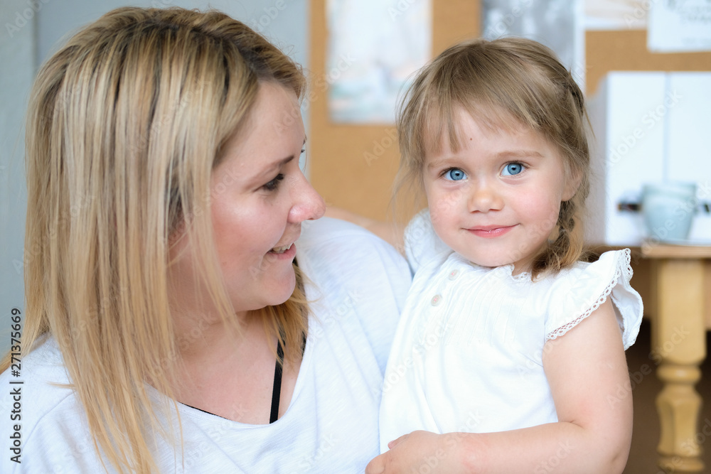 Mother and daughter. A young blonde woman with her beautiful little daughter. The girl has blue eyes and blonde braids.