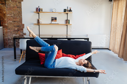 Young beautiful woman have fun at home resting on couch in her apartment.