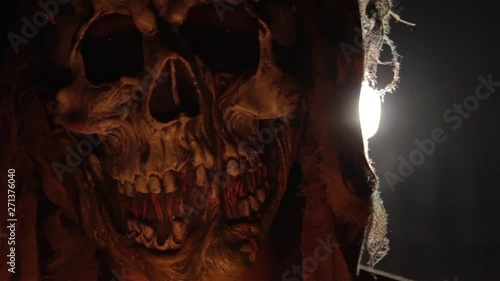 Man with scary halloween mask holding candles back lit by light. Black magic ritual or scary halloween rite