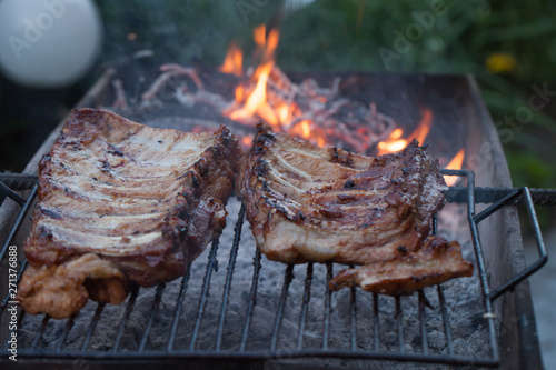 Grilled barbeque port. Cooking outdoor. Marinated grilled ribs. Summer picnic. Cooking dinner. Spareribs Ribs Close-up On The Hot Flaming Grill.