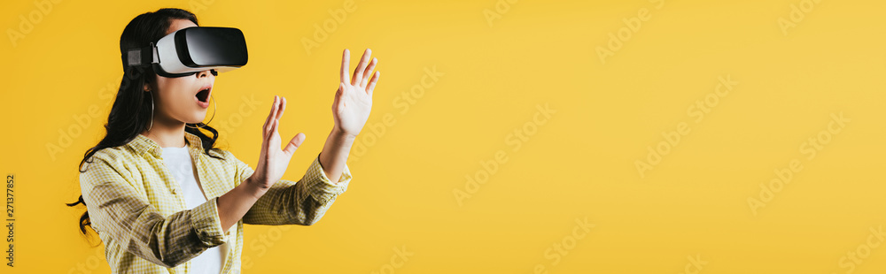 surprised woman gesturing and using Virtual reality headset, isolated on yellow surprised woman gesturing and using Virtual reality headset, isolated on yellow