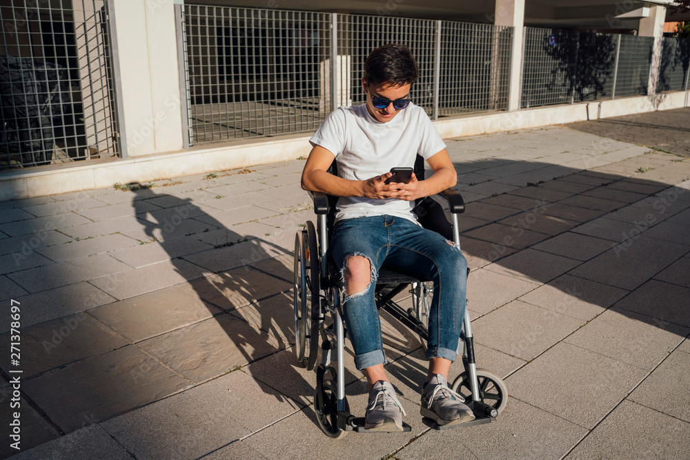 Obraz premium Portrait of cute boy sitting on wheelchair outdoor