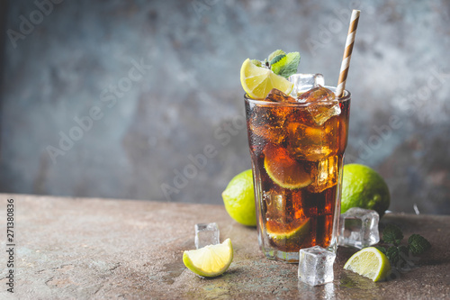 Fresh made Cuba Libre with brown rum, cola, mint and lemon on gray stone background photo