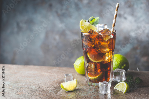 Fresh made Cuba Libre with brown rum, cola, mint and lemon on gray stone background