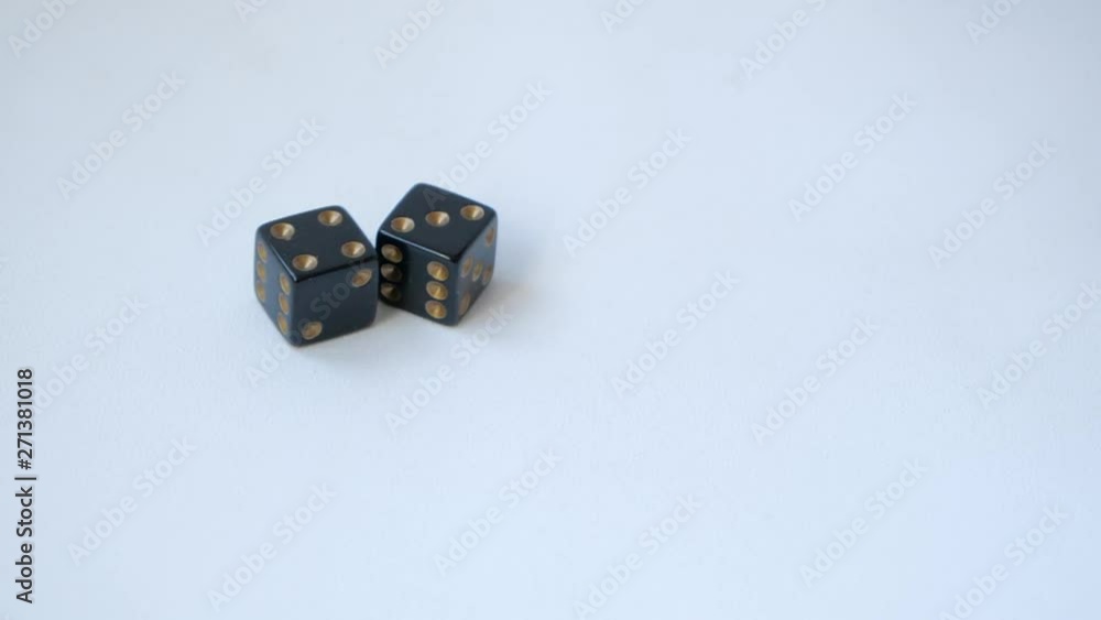Rolling a four and a three with a pair of black gambling dice on a white table in slow motion Rolling a four and a three with a pair of black gambling dice on a white table in slow motion