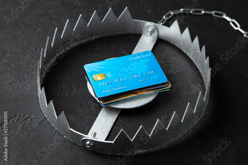 Trap with stack of credit cards. Unsafe credit risk. Black background.
