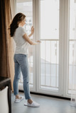 Beautiful young woman opening window in the morning