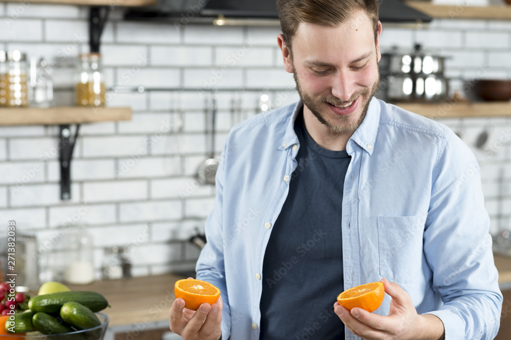 Man looking at two orange slices in kitchen Man looking at two orange slices in kitchen