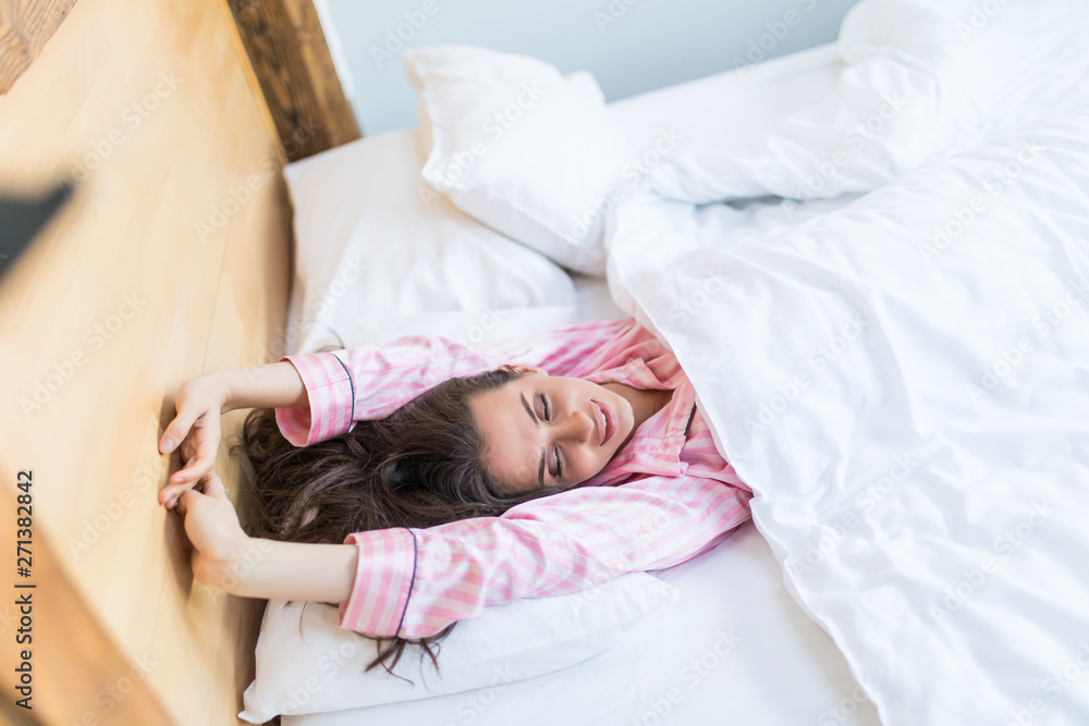 Happy young girl waking up stretching arms on the bed in the morning Happy young girl waking up stretching arms on the bed in the morning