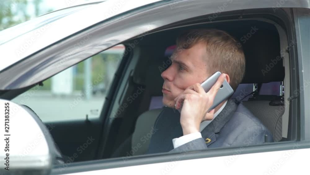 Serious Businessman Eating a Burger while Sittting in the Car and Talking on Phone. Lunch Break. Lifestyle and Business Concept Serious Businessman Eating a Burger while Sittting in the Car and Talking on Phone. Lunch Break. Lifestyle and Business Concept