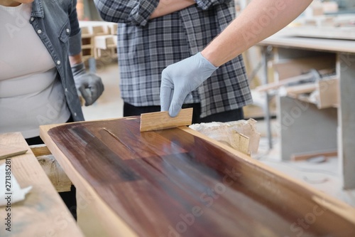 Closeup of workers hand covering wooden plank with finishing protective cover for wood