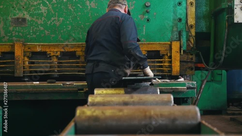 A man works on a cutting machine. Back view. photo