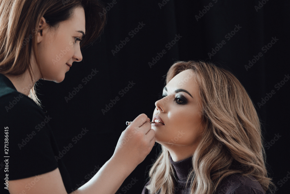 Beauty shop. Make up. Stylish paints lips with a brush to client. Beauty shop. Make up. Stylish paints lips with a brush to client.