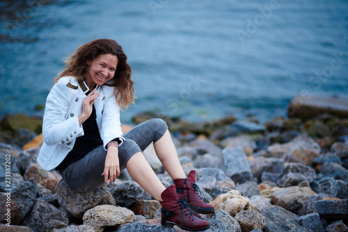 fashionable girl dressed in white jacket and wide trousers posing near sea in the evening © soleg