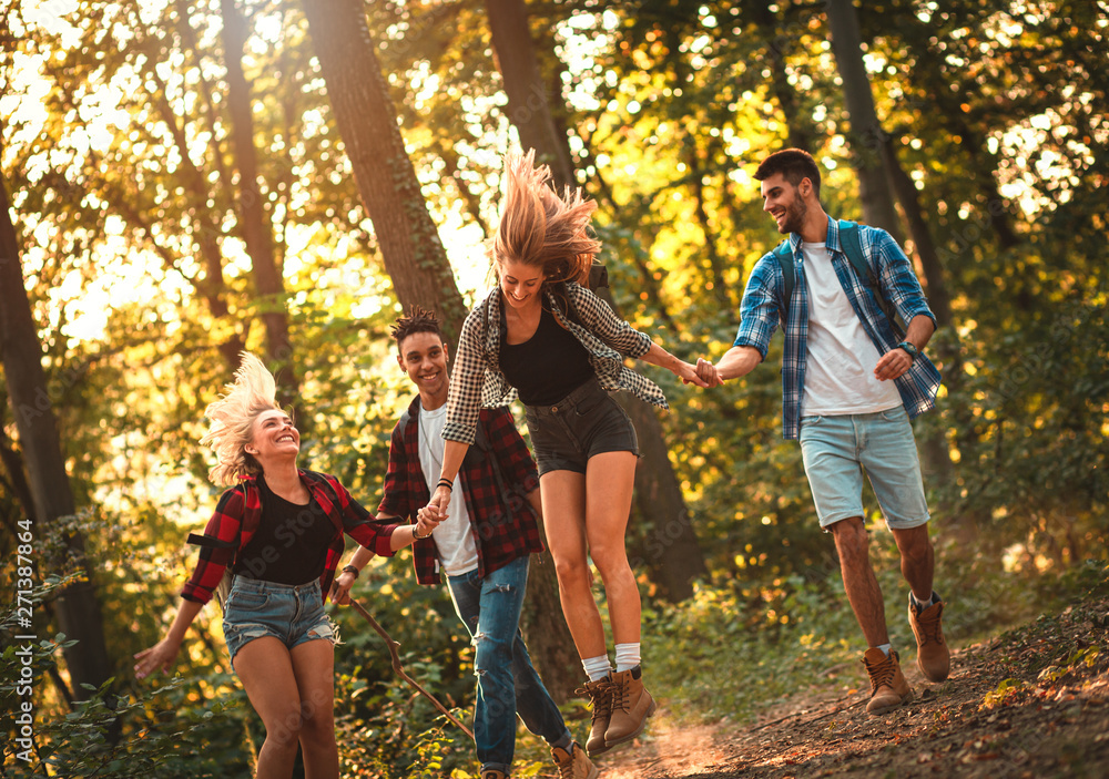 Group of four friends having fun hiking through forest together. Group of four friends having fun hiking through forest together.