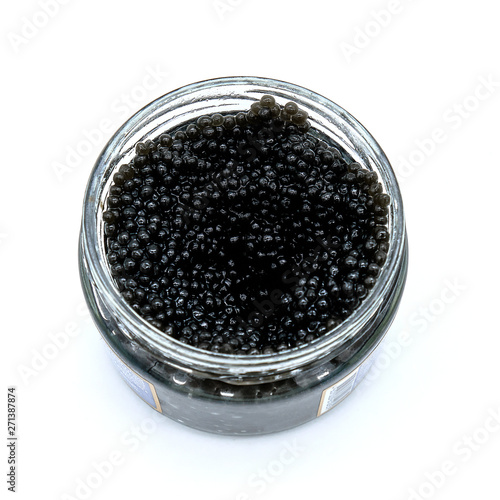 Open glass jar of black caviar on isolated white background. A delicacy made from the eggs of sturgeon. Luxury food from Volga in Russia. Top view of the jar with black caviar Beluga.