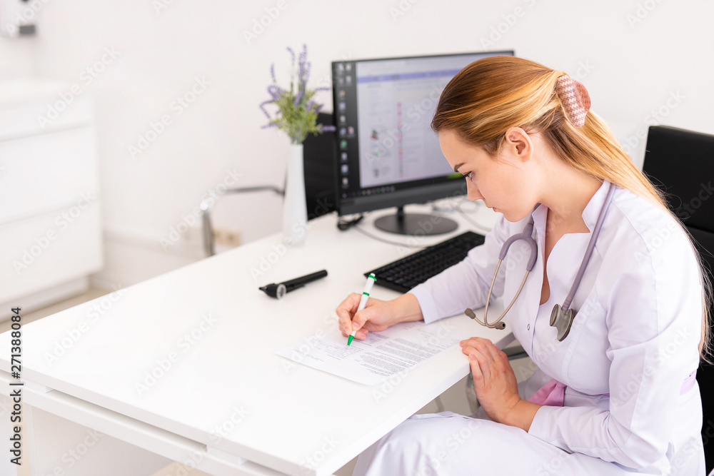 Young blonde doctor working on computer in new clinic. Helthcare concept Young blonde doctor working on computer in new clinic. Helthcare concept