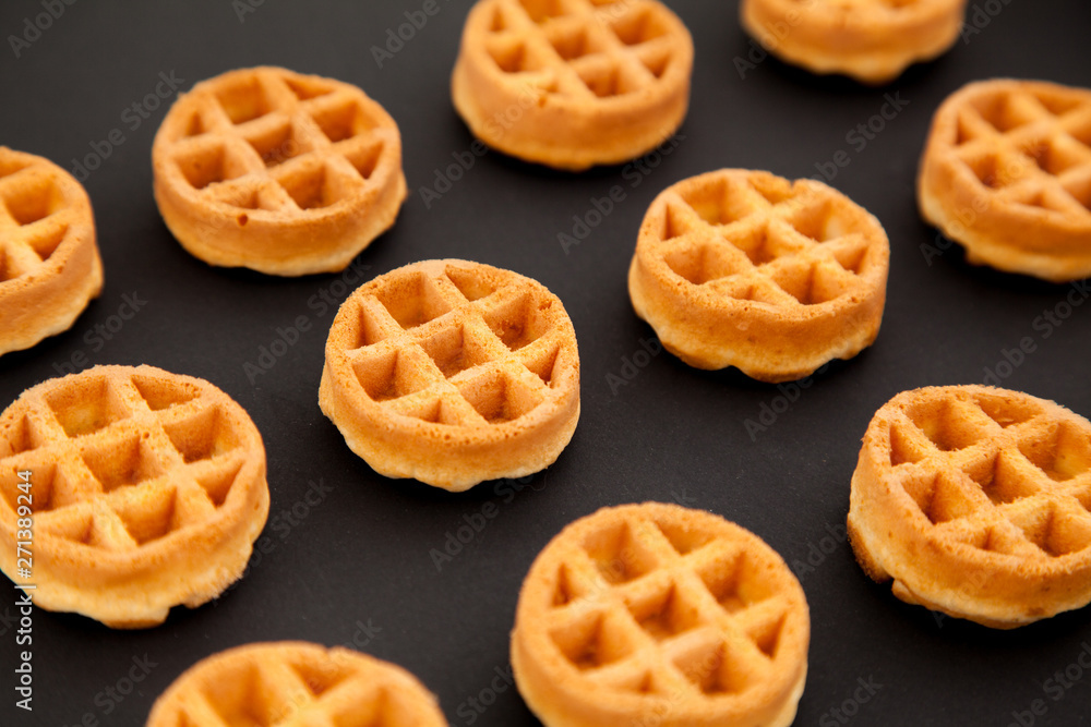 round little Viennese waffles on a black background top in perspective. Sweet background