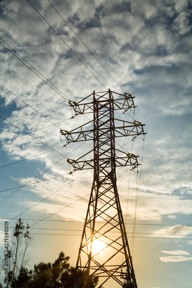 View of the power line against the clouds of blue sky in the sunlight. Electric, technology.