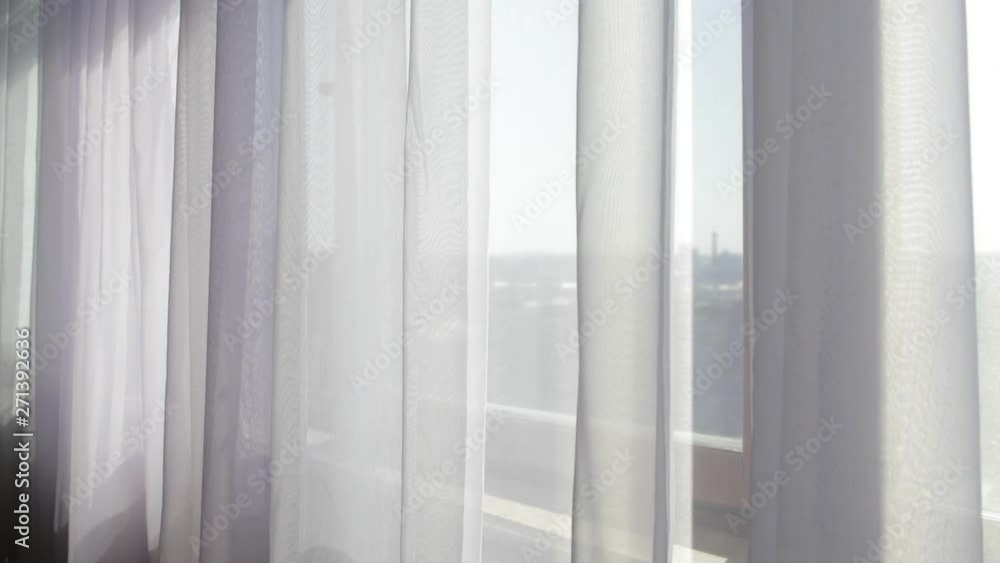 Moving grey curtains at wide window Moving grey curtains at wide window