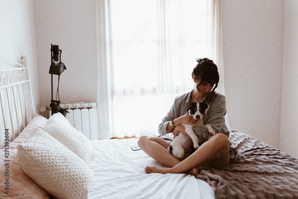 Brunette woman hugging her sweet labrador puppy in bedroom Brunette woman hugging her sweet labrador puppy in bedroom