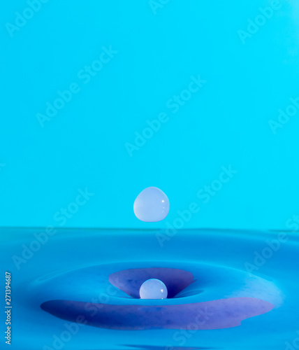 water droplet falling and impacting a body of water and shaping splashes