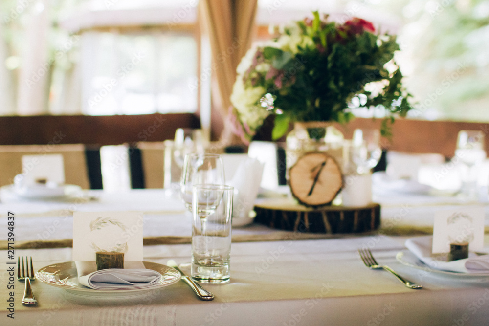 Beautiful decorated elegant wedding table for dinner with floral white bouquets, candlesticks and a white tablecloth glasses and porcelain plates Beautiful decorated elegant wedding table for dinner with floral white bouquets, candlesticks and a white tablecloth glasses and porcelain plates