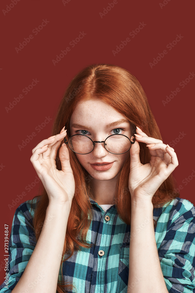 Looking at you. Portrait of cheerful redhead girl touching glasses Looking at you. Portrait of cheerful redhead girl touching glasses