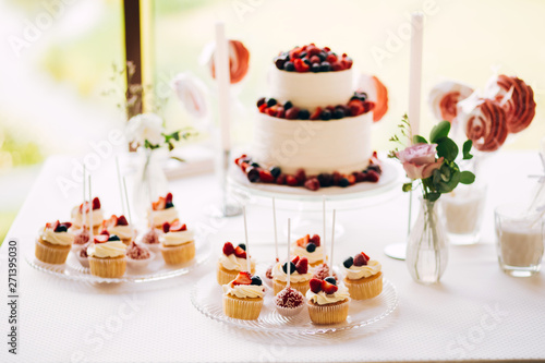 Beautiful cake covered with icing cream, summer berries on the top. Style and food photography
