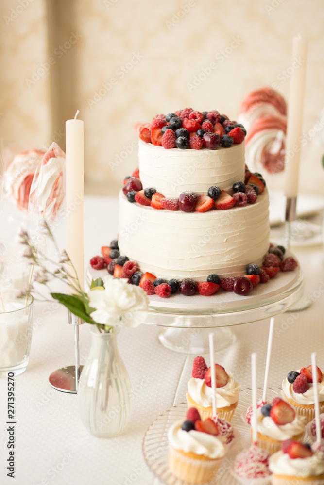 Beautiful cake covered with icing cream, summer berries on the top. Style and food photography Beautiful cake covered with icing cream, summer berries on the top. Style and food photography