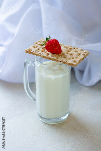 milk in a glass for beer. dry dietary bread, red strawberries on a white wooden kitchen table, morning, breakfast fitness and food cooking. white background, healthy lifestyle