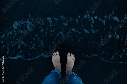 Black magnetic sand beach of Black sea in Ureki, Georgia. Rest on black sea trip to the sea of Georgia. two mans feet in the dark sand by the sea. Man's legs on the sand beach photo