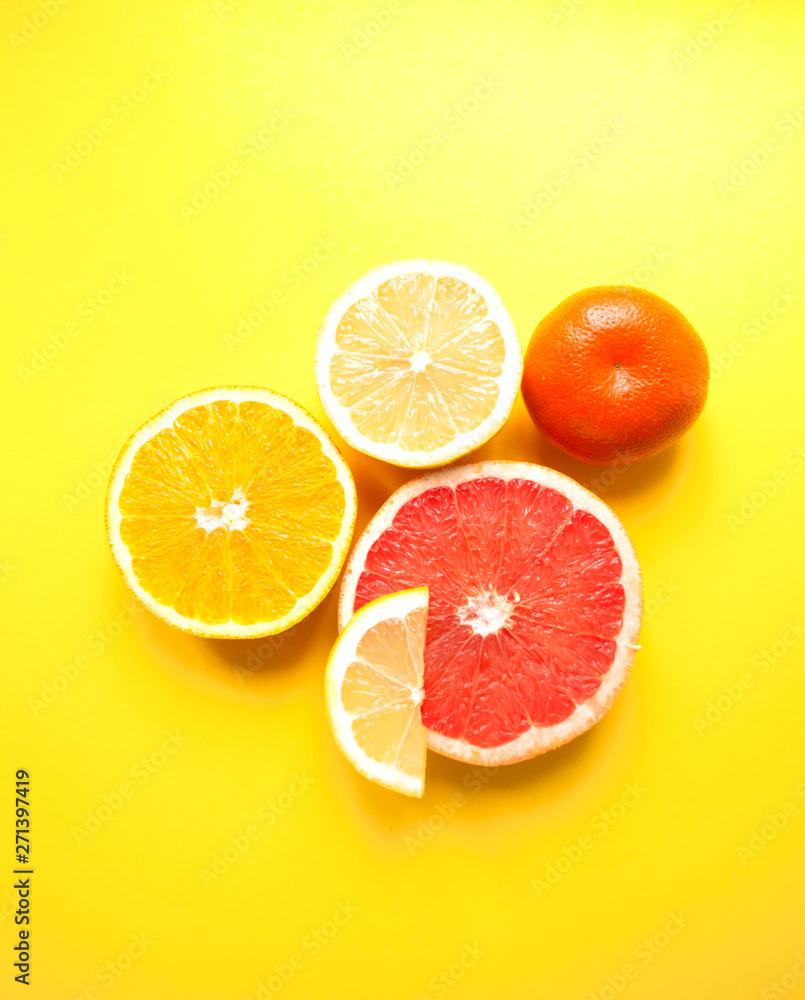 Flat lay of cut ripe juicy grapefruit, lemon and orange on yellow background. Citrus pattern. Flat lay of cut ripe juicy grapefruit, lemon and orange on yellow background. Citrus pattern.