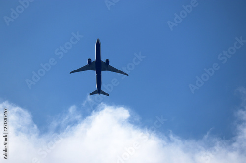 Airplane in the blue sky with white clouds. Commercial plane in a flight close up, bottom view