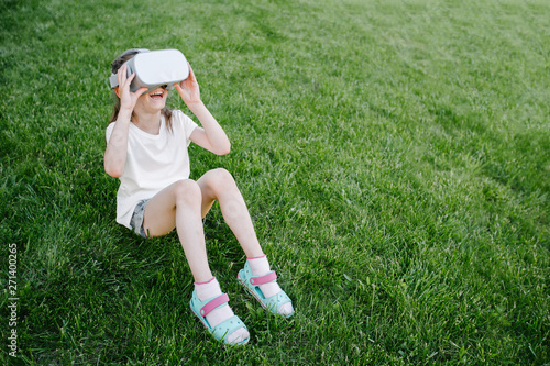 Kid girl using virtual reality glasses outside