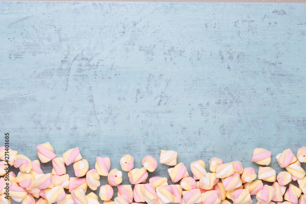 Marshmallows on blue background with copyspace. Flat lay or top view. Background or texture of colorful mini marshmallows. Marshmallows on blue background with copyspace. Flat lay or top view. Background or texture of colorful mini marshmallows.