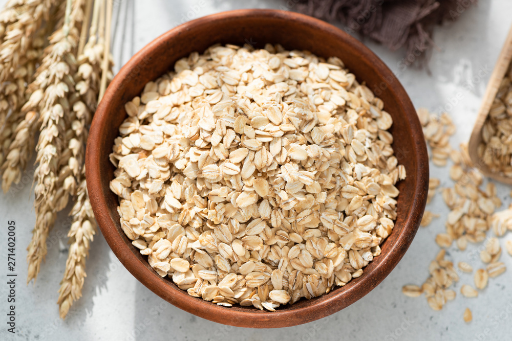 Oats or Oat Flakes in bowl, grey concrete background, top view. Healthy eating concept, weight loss and dieting Oats or Oat Flakes in bowl, grey concrete background, top view. Healthy eating concept, weight loss and dieting
