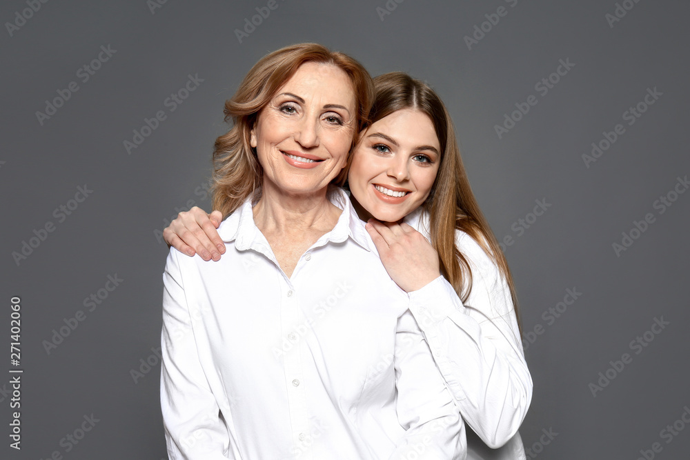 Portrait of happy mother with her daughter on grey background Portrait of happy mother with her daughter on grey background