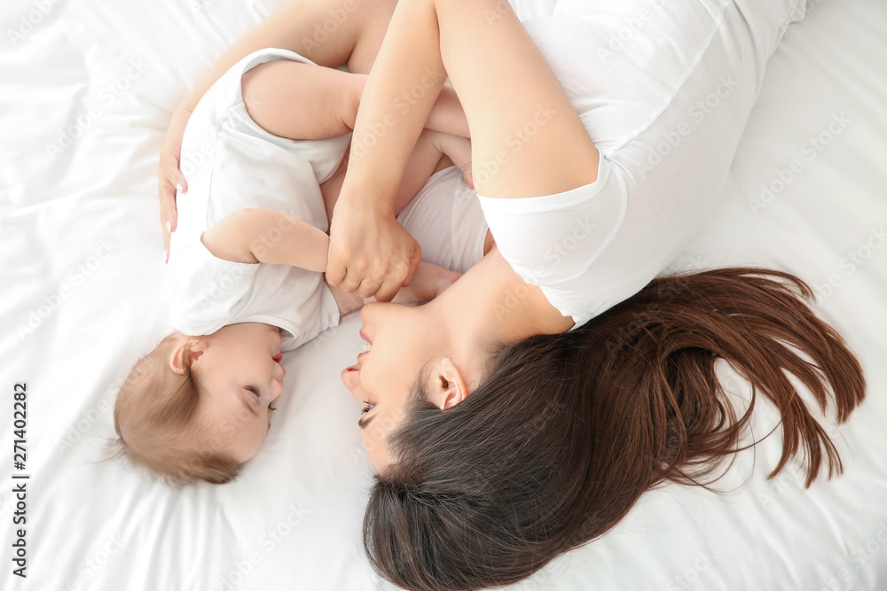 Happy mother with cute little baby lying on bed Happy mother with cute little baby lying on bed
