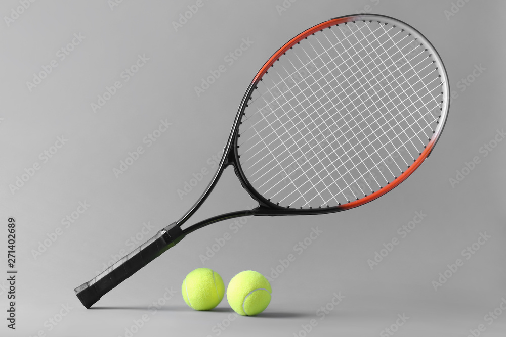 Tennis racket and balls on grey background