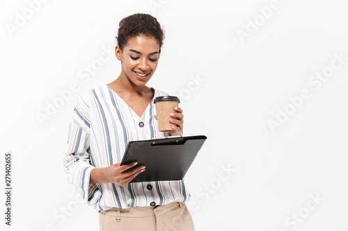 Beautiful african woman posing isolated over white wall background drinking coffee holding clipboard.