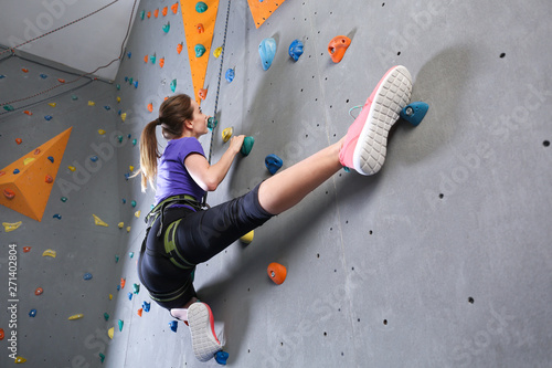 Young woman climbing wall in gym