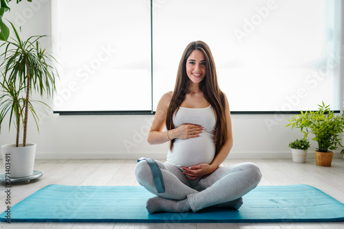 Obraz na plátně Portrait of happy smiling beautiful pregnant fitness woman at home