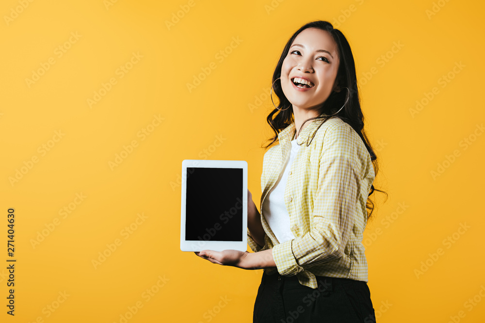 happy asian woman showing digital tablet with blank screen, isolated on yellow happy asian woman showing digital tablet with blank screen, isolated on yellow