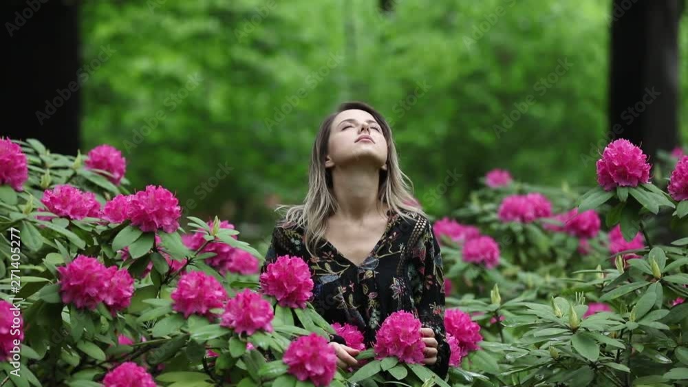 style woman near rhododendron flowers in a garden in spring time style woman near rhododendron flowers in a garden in spring time